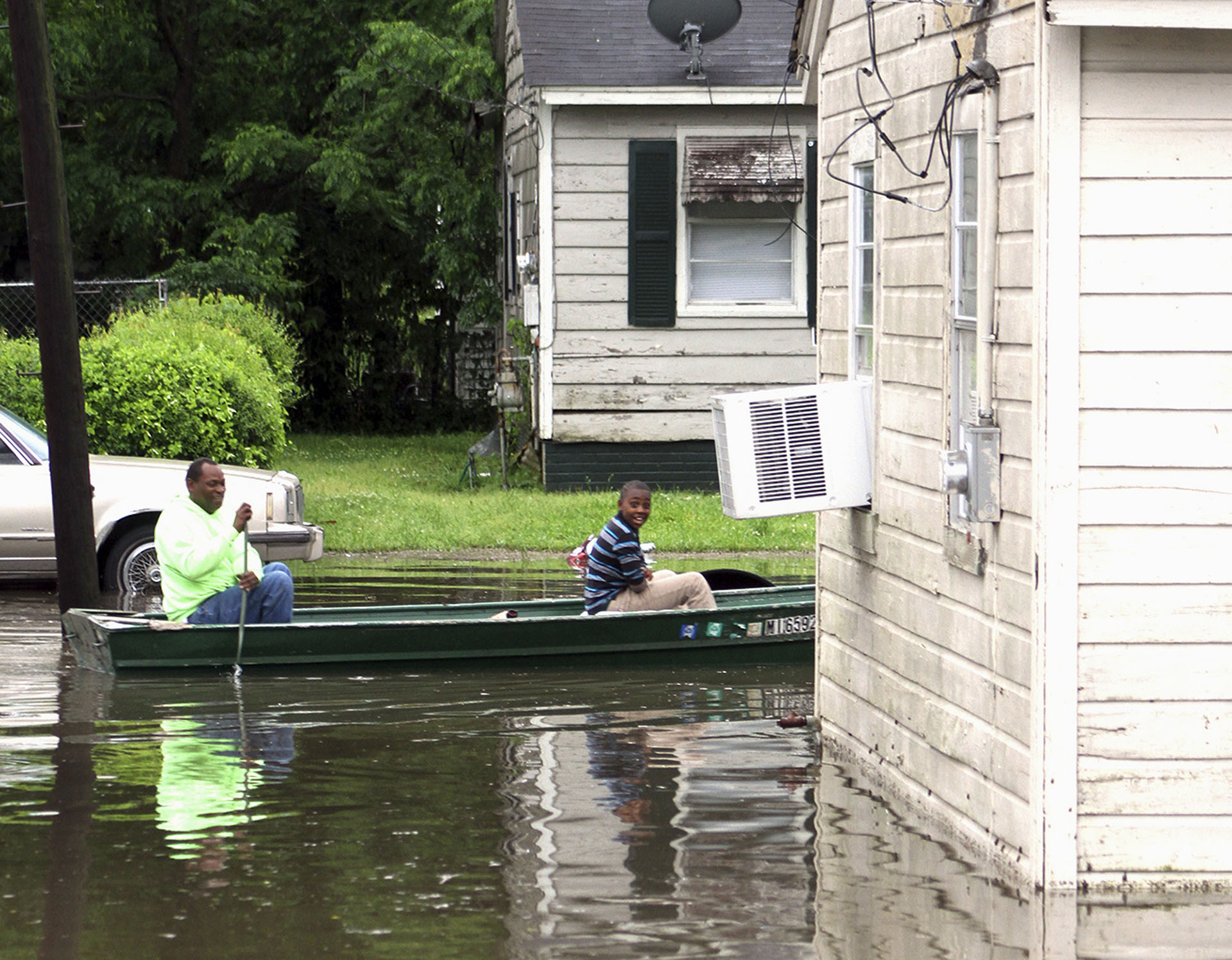 Clarance Ferguson, a la izquierda, y su nieto Demarious Ferguson navegan en su barco por la larga calle Hugh en el sur de Greenville, Misisipi, el jueves 9 de mayo de 2019. (AP)