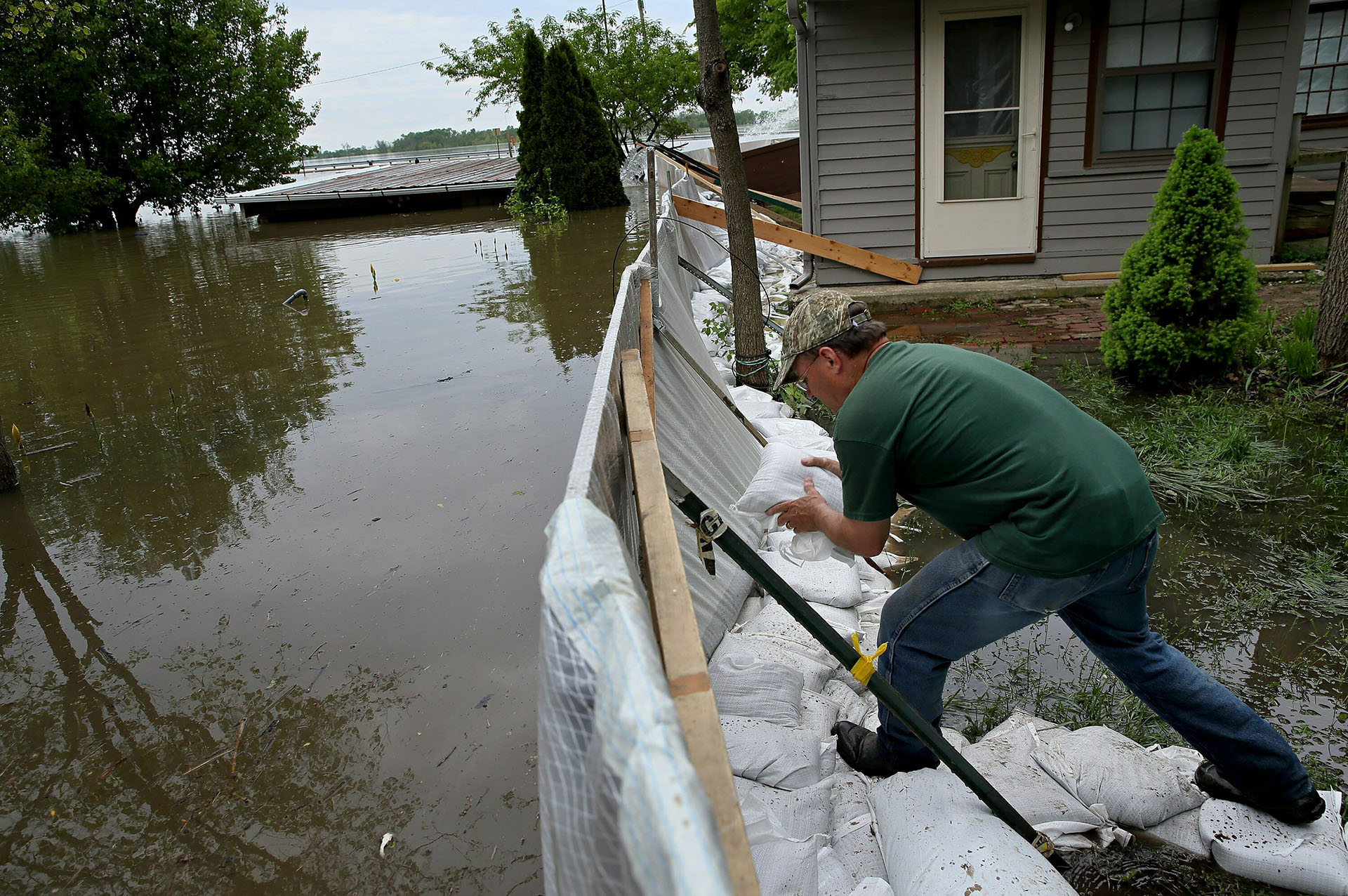 Alley Ringhausen utiliza bolsas de arena para reforzar el muro que él y otros voluntarios construyeron alrededor de la Riverview House en Elsah, Illinois, a medida que el agua de la inundación del río Misisipi se filtra a través de una barrera improvisada el lunes 6 de mayo de 2019. (AP)