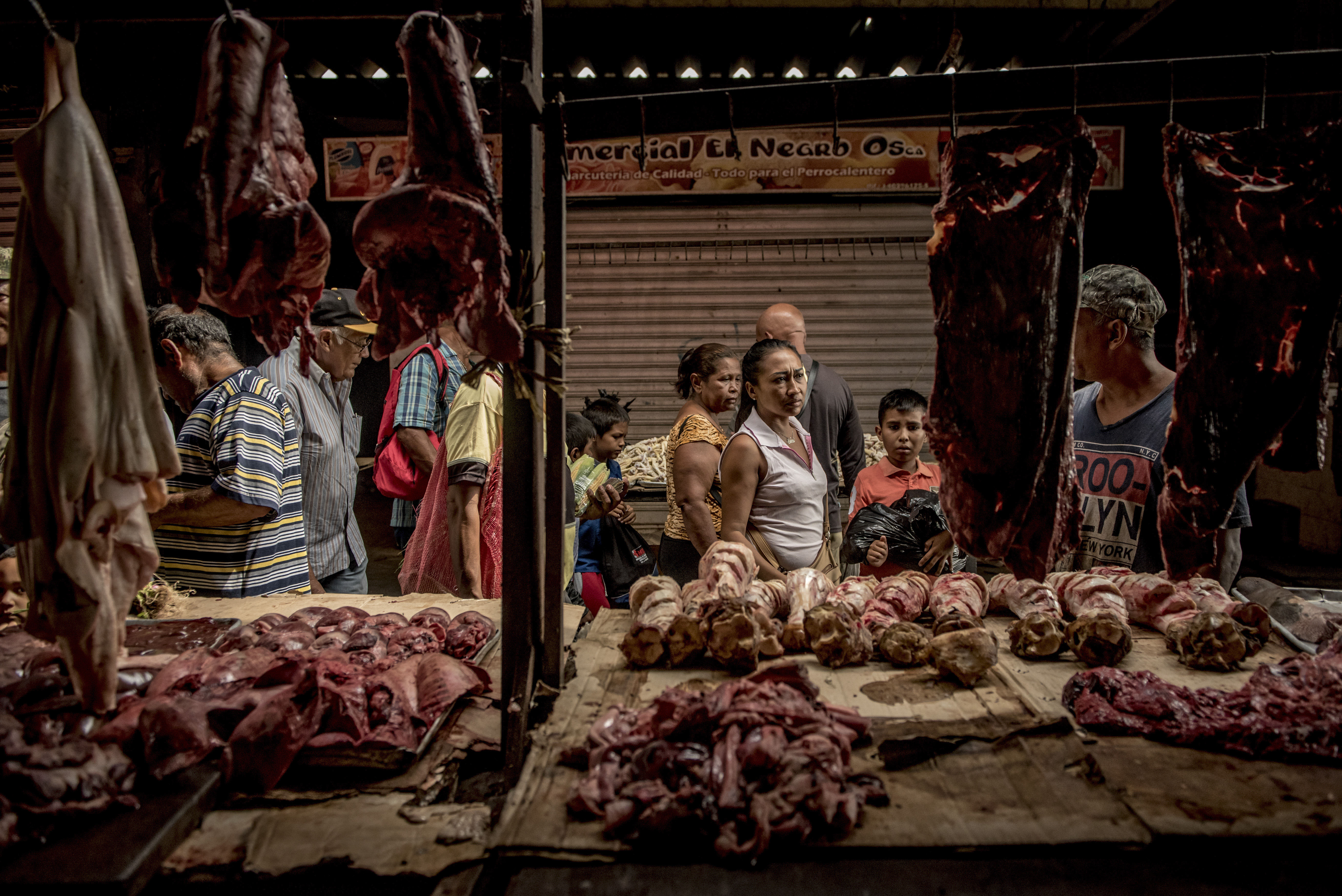 Personas que compraban despojos no refrigerados y otros subproductos de carne de res en un mercado de Maracaibo. (Meridith Kohut/The New York Times)