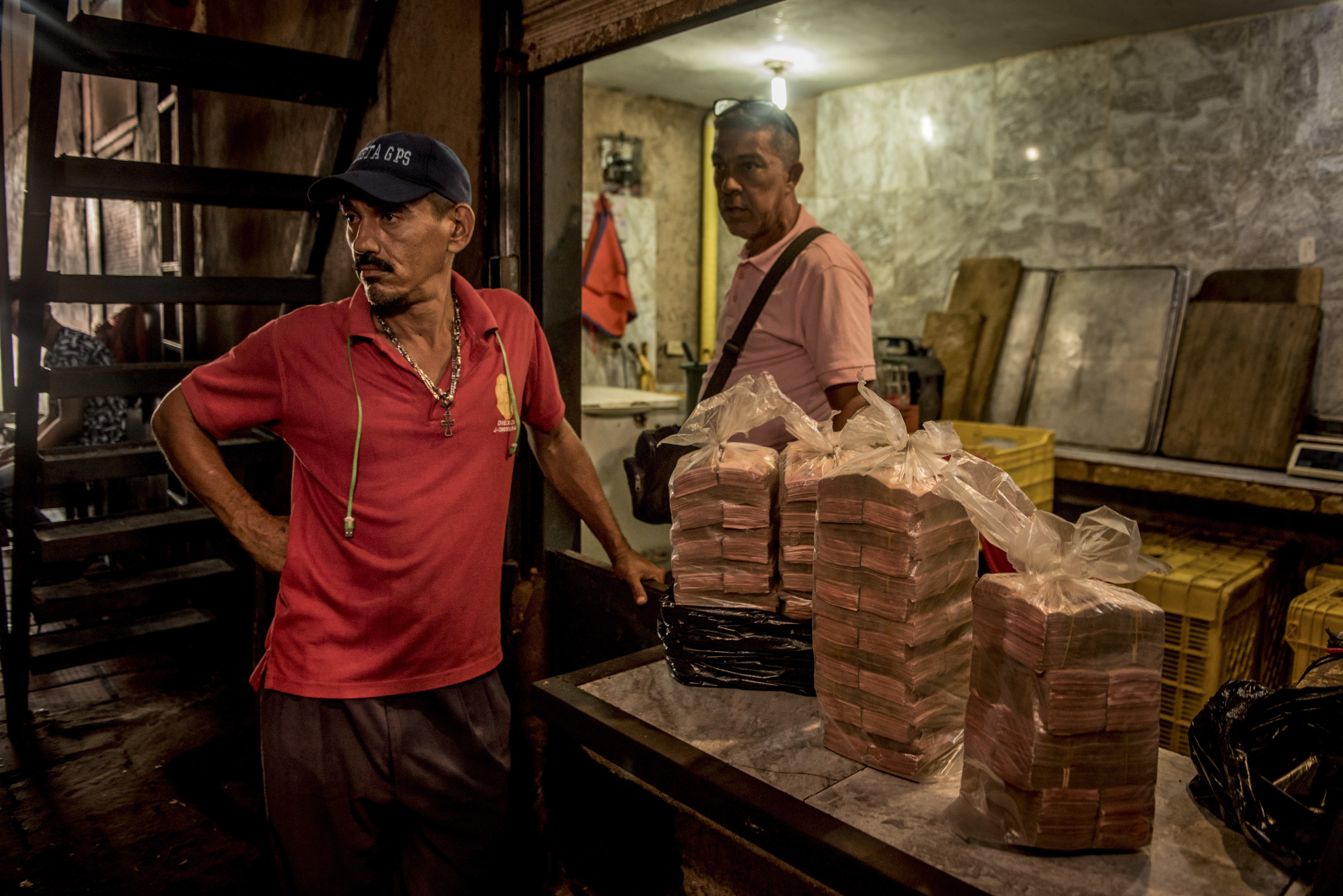 Vendedores con bolsas de dinero, que ha perdido buena parte de su valor, en un puesto del mercado Las Pulgas en Maracaibo. (Meridith Kohut/The New York Times)