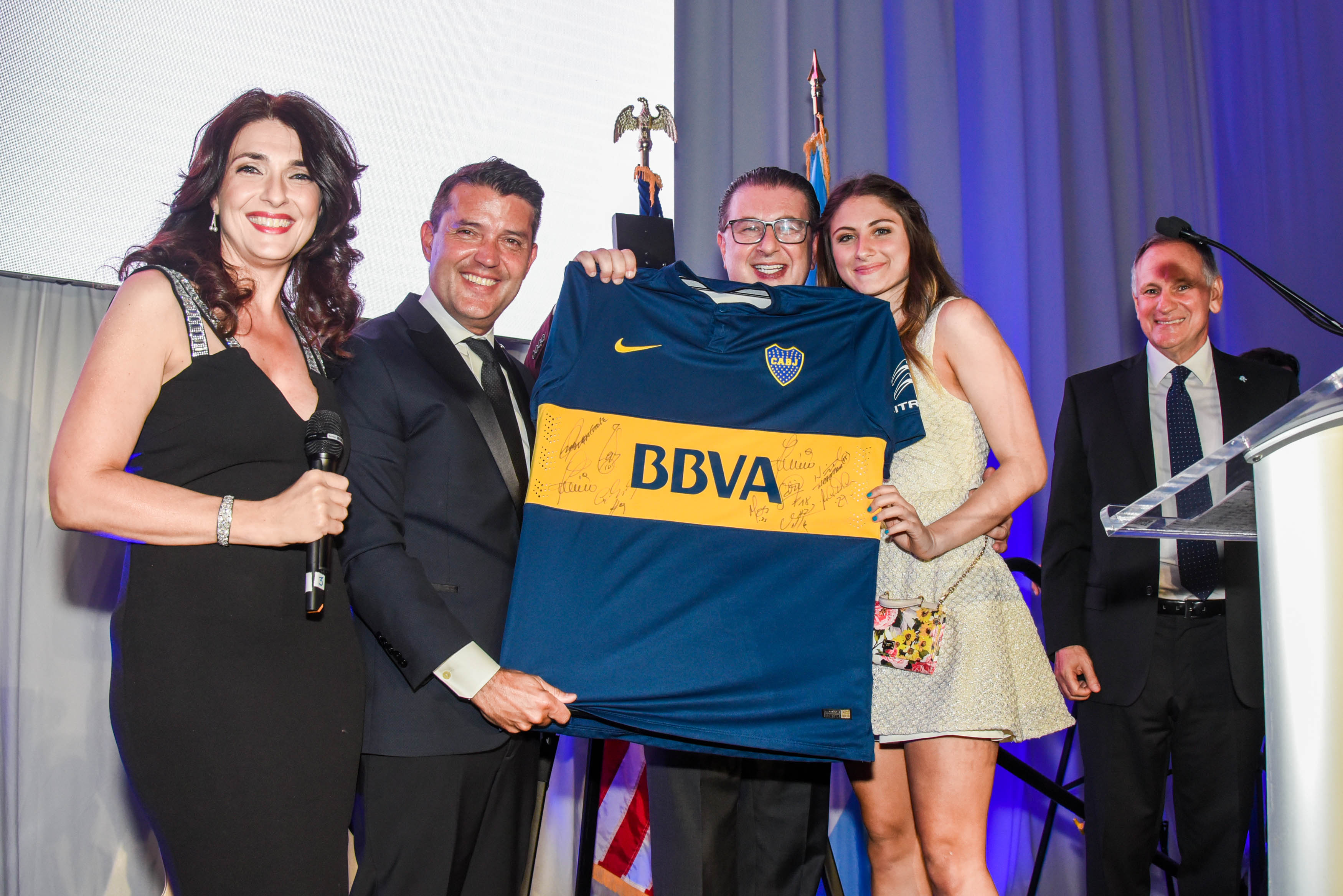 Fátima Slame, presentadora del evento, y Diego Molinari, Vicepresidente 1ro. De la AACC, entregan la camiseta del CABJ a Sergio Codino y su hija