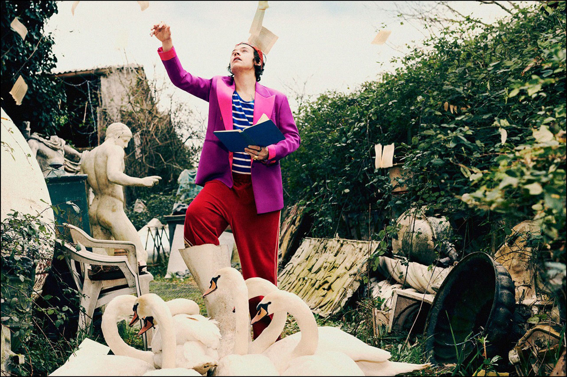 Harry Styles desprende las páginas de un libro en medio de un jardín rodeado de cisnes.