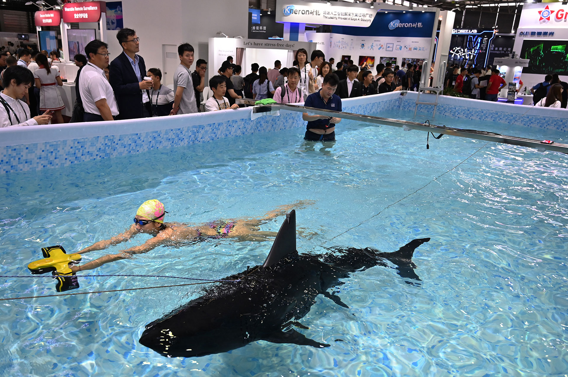 Una mujer nada junto a un robot submarino durante el Consumer Electronics Show, Ces Asia 2019 en Shanghai el 11 de junio de 2019. (AFP)