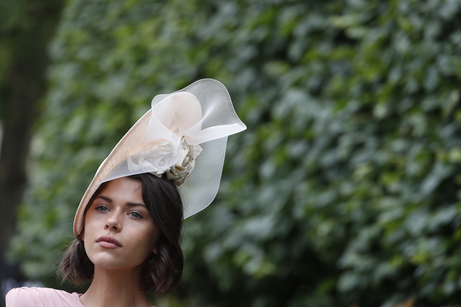 Fascinator plato con red y aplique de flor realizado en tela. Al evento suelen recurrir destacadas personalidades británicas y modelos