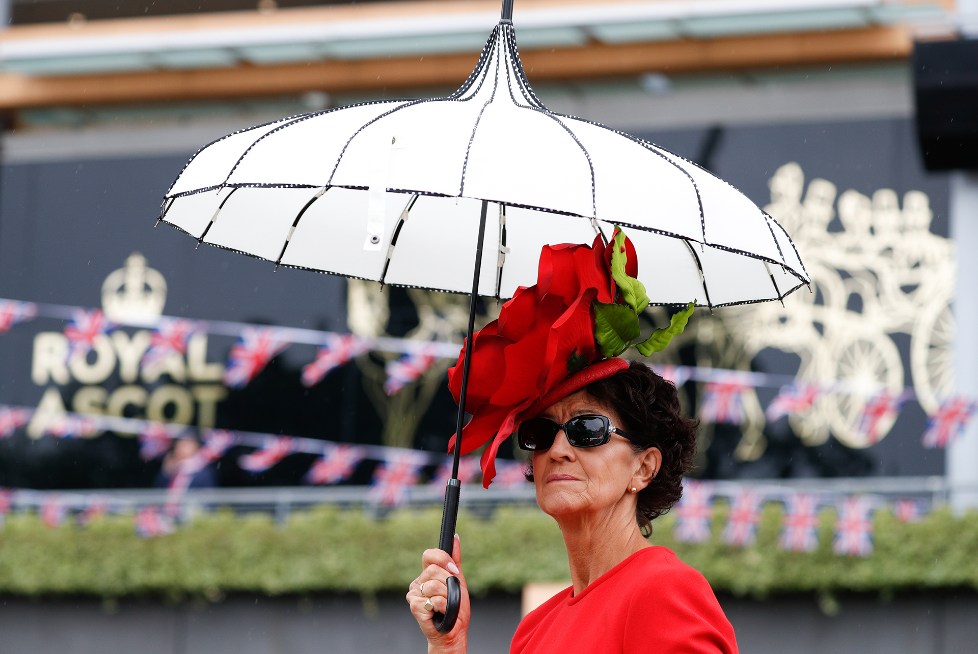 Un fascinator en rojo con una mega flor rosa con tallo verde