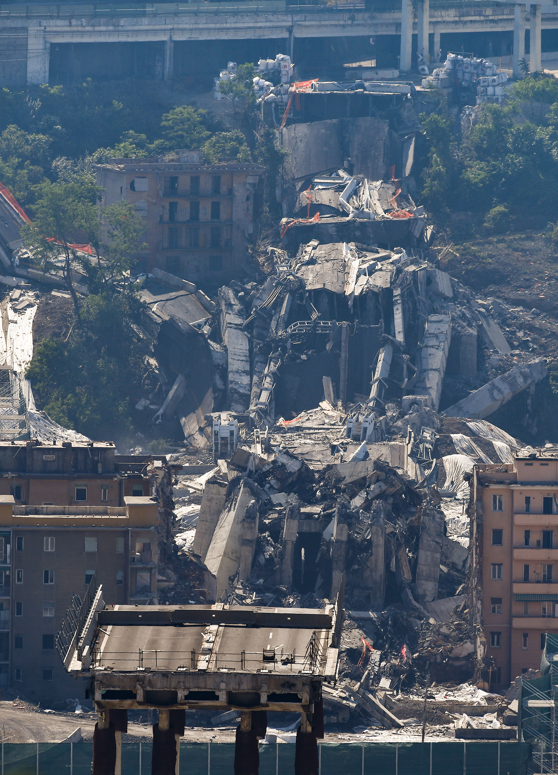 El tablero del puente, entre los escombros y los edificios evacuados después de que cargas explosivas volaran los pilones (AFP)
