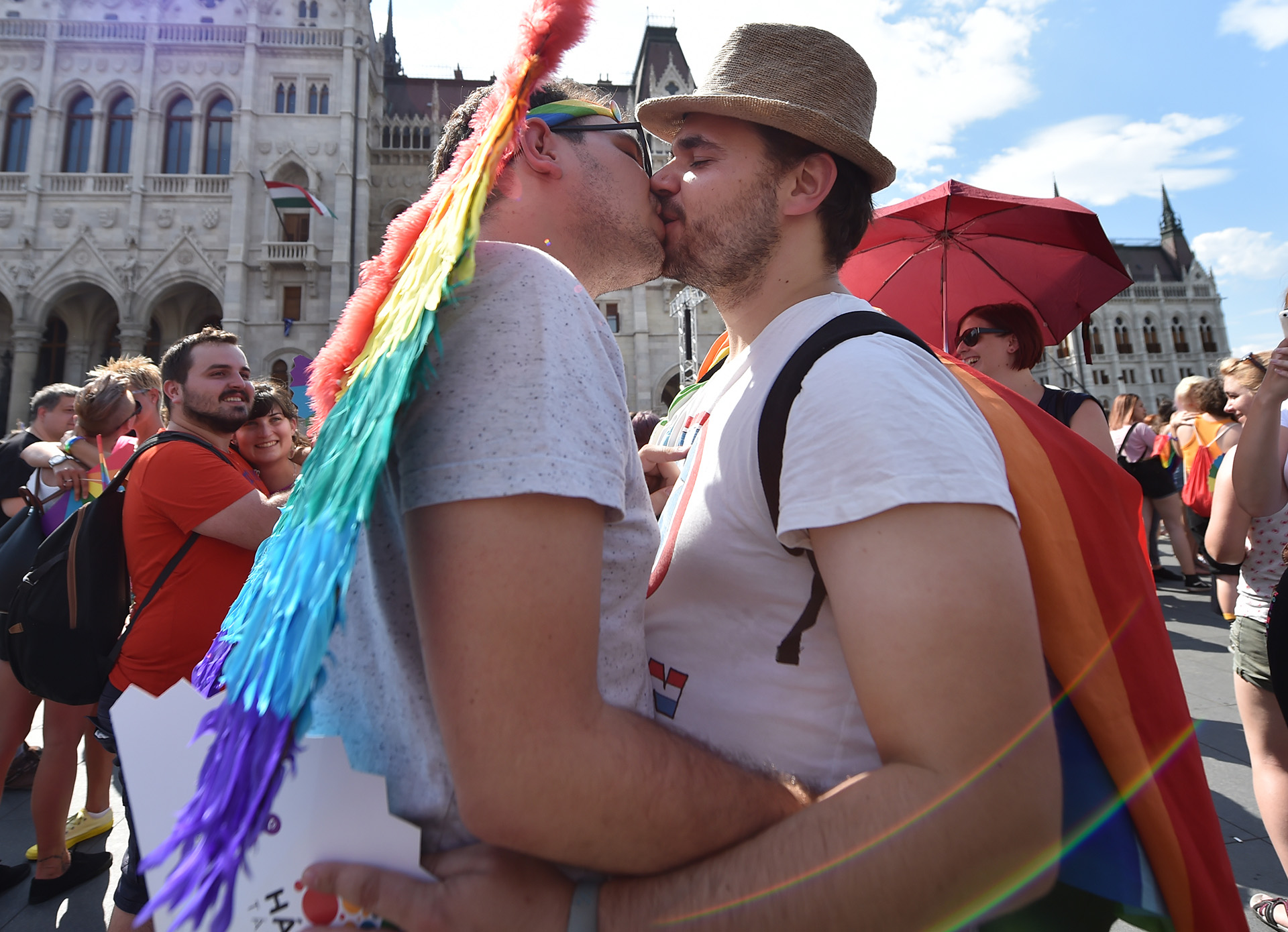 Vistiendo los colores del arco iris, una joven pareja besa durante un flashmob frente al edificio del parlamento en el centro de Budapest durante el desfile de orgullo de lesbianas, gays, bisexuales y transexuales (LGBT) en la capital húngara el 6 de julio de 2019.