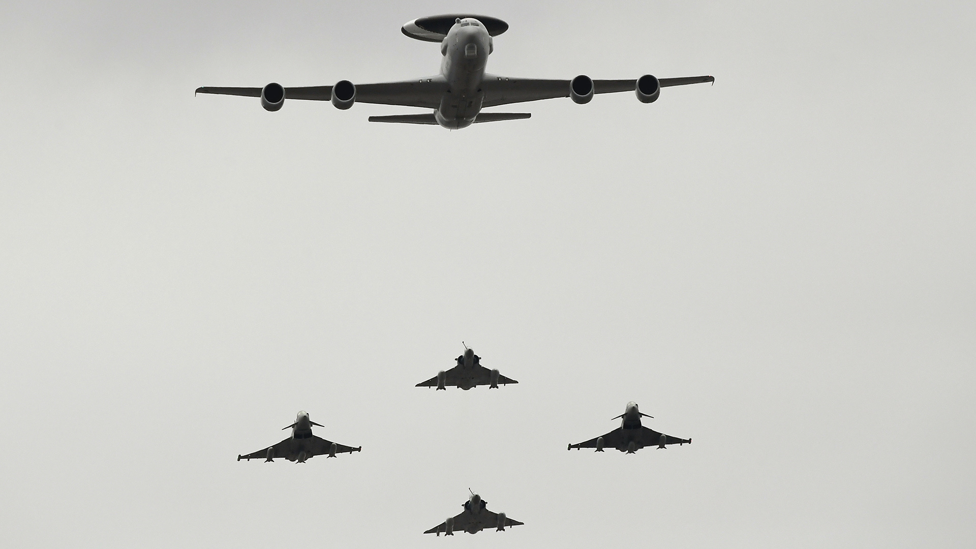 Aviones militares sobre París: Boeing E-3 Sentry (arriba), Mirage 2000 (vertical, rombo) y Eurofighter Typhoon (izquierda y derecha)