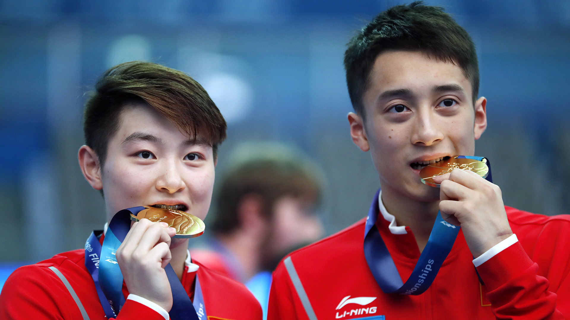Los chinos Si Yajie y Lian Junjie “prueban” sus medallas de oro