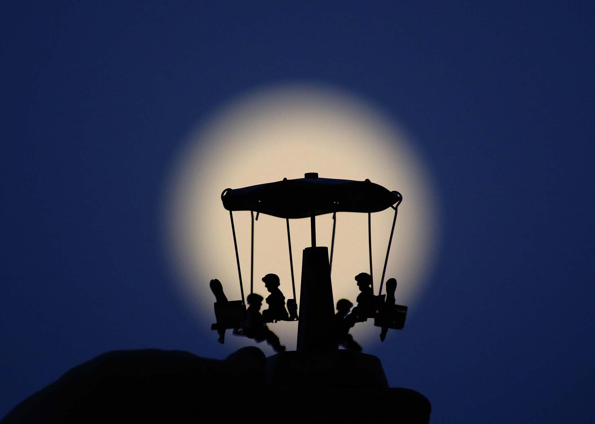 Una luna llena frente a un carrusel en Nicosia, Chipre (EFE/EPA/KATIA CHRISTODOULOU)