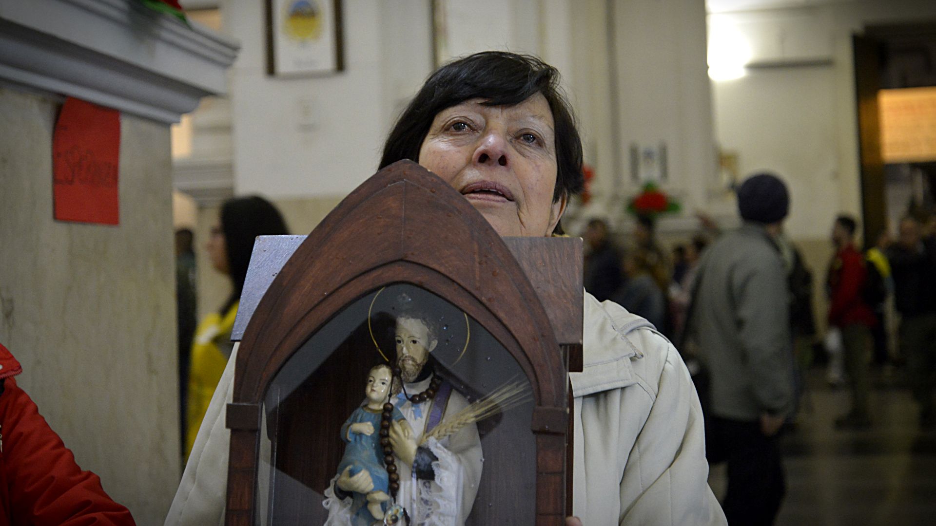 Una mujer ingresa al santuario con una figura del patrono del trabajo, un ritual que se repite año tras año entre muchos de los feligreses