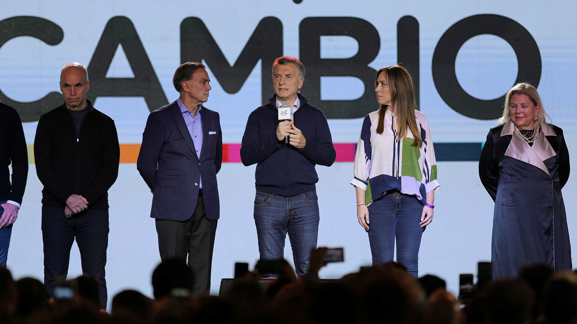 Maria Eugenia Vidal con camisa de seda geométrica beige combinada verde oliva, celeste y azul, con jeans oxford. Miguel Angel Pichetto fiel a su estilo con el saco y pantalón y su camisa celeste