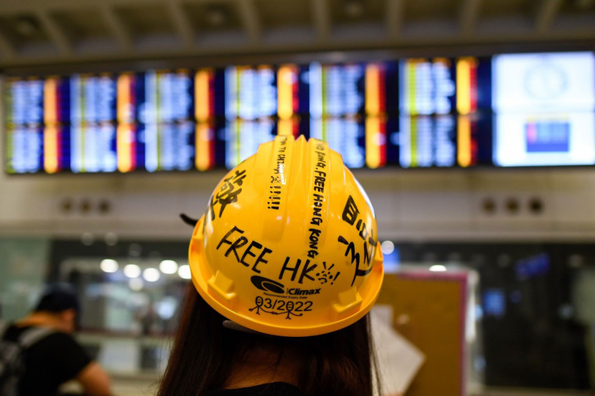 Una joven observa el tablero de anuncios de vuelos cancelados durante la protesta contra la brutalidad policial y el controvertido proyecto de ley de extradición en Hong Kong (Foto de Manan VATSYAYANA / AFP)