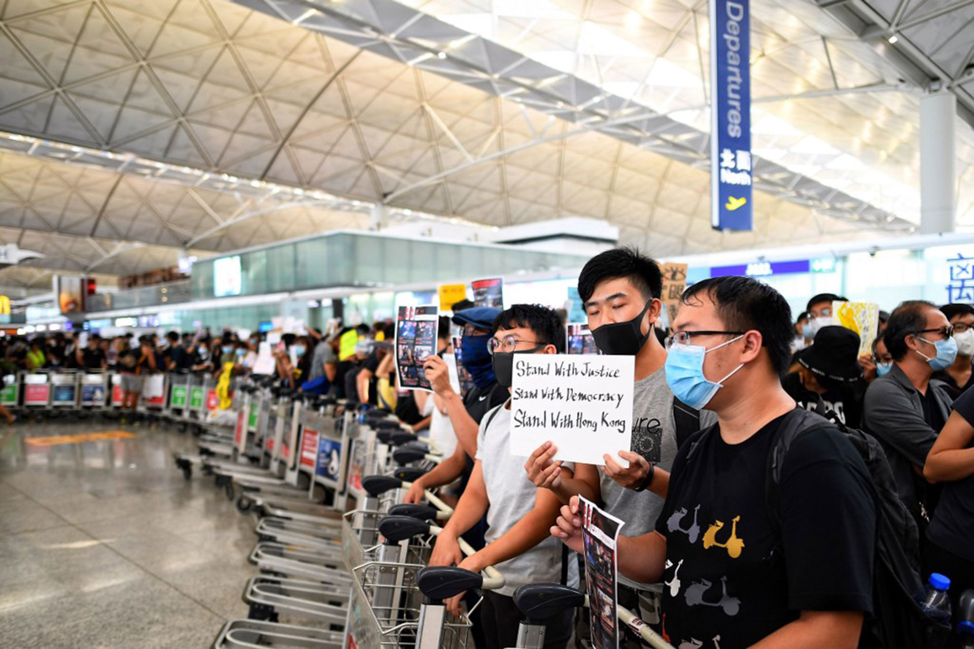 Los manifestantes traban el paso de los pasajeros en los pasillos de salida del aeropuerto de Hong Kong, un día después de que una sentada obligara a las autoridades a cancelar todos los vuelos hacia y desde la terminal (Foto de Manan VATSYAYANA / AFP)