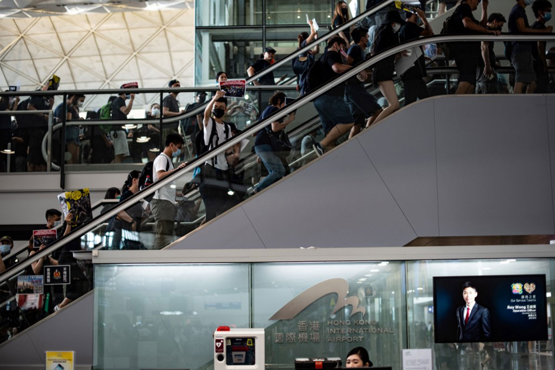 Los manifestantes cantan consignas mientras suben por las escaleras mecánicas del aeropuerto (Foto de Philip FONG / AFP)