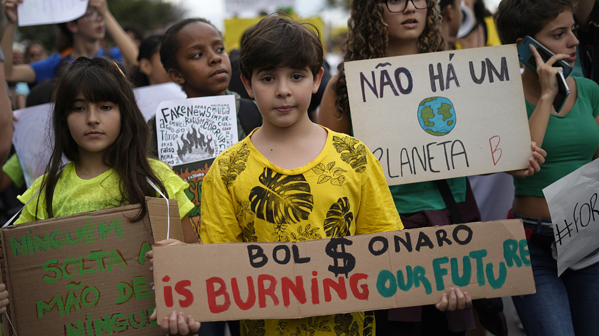 Un niño sostiene un cartel que dice “Boslonaro esta quemando nuestro futuro”. (Foto por Mauro PIMENTEL / AFP)