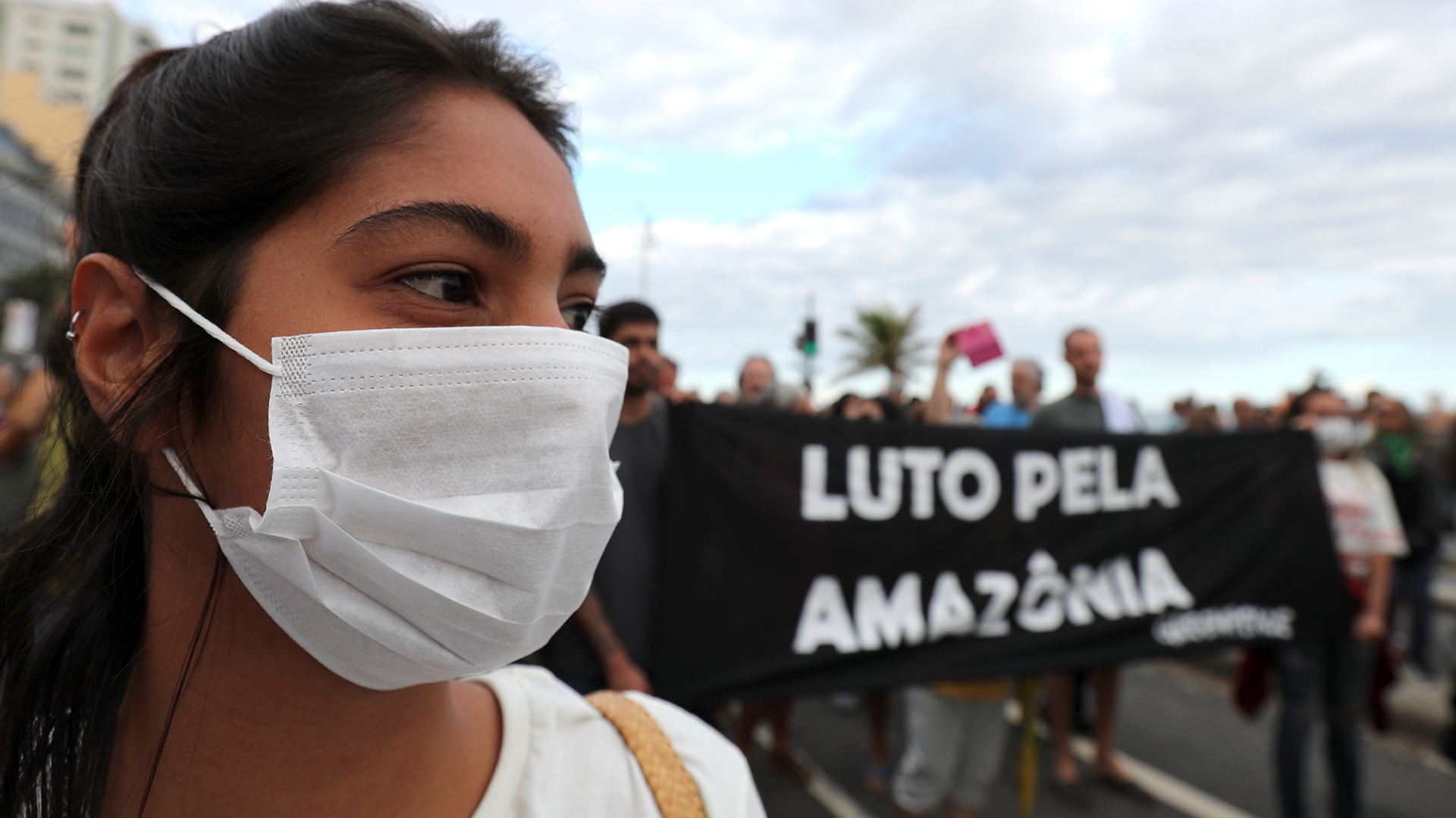 Una mujer con una máscara asiste a una manifestación para exigir más protección en el Amazonas. El letrero que se encuentra detrás dice “Luto por la Amazonia”. REUTERS / Sergio Moraes