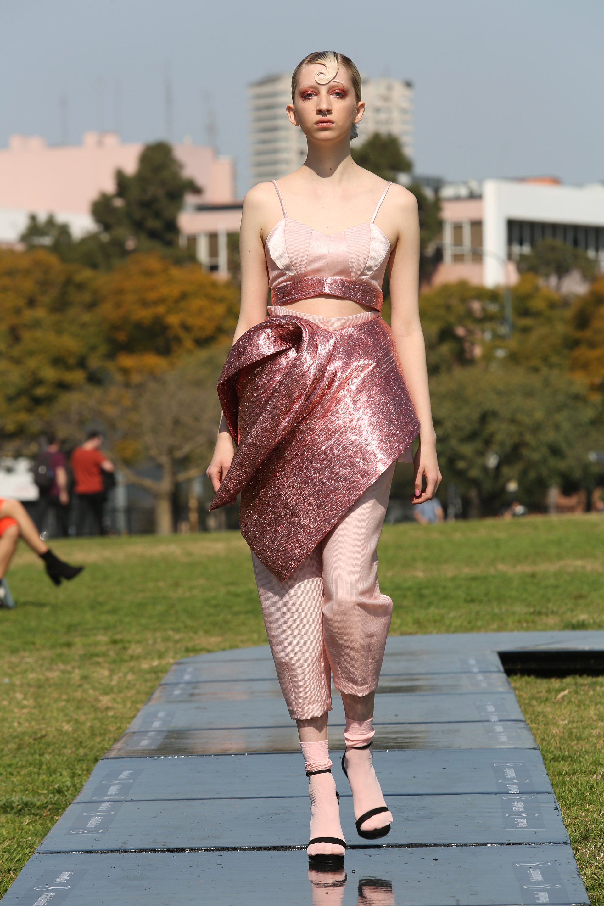 Conjuntos de dos piezas, con detalles metalizados y con glitter, inspirados en los años 50 y 60, los diseños haute couture, tuvieron como escenario la Floralis Generica en Palermo