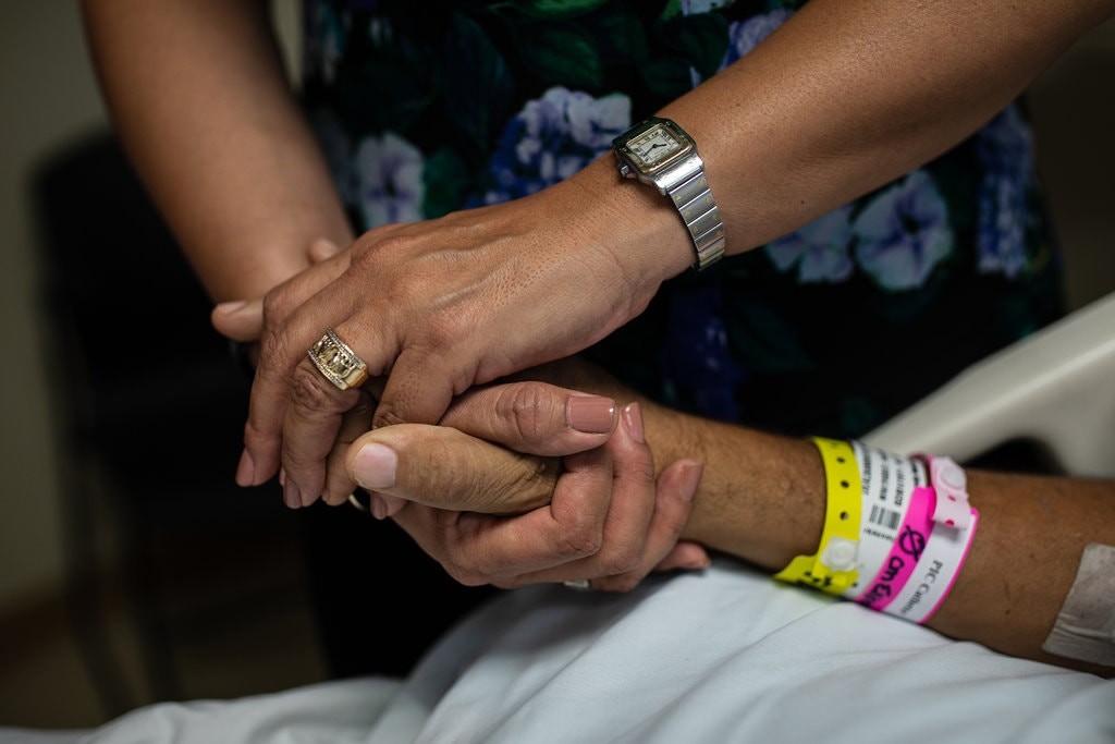 La hermana de De Alba sostiene la mano de Mario, quien se dedica a reparar lavadoras y secadoras en México (Foto: Tamir Kalifa/The New York Times)
