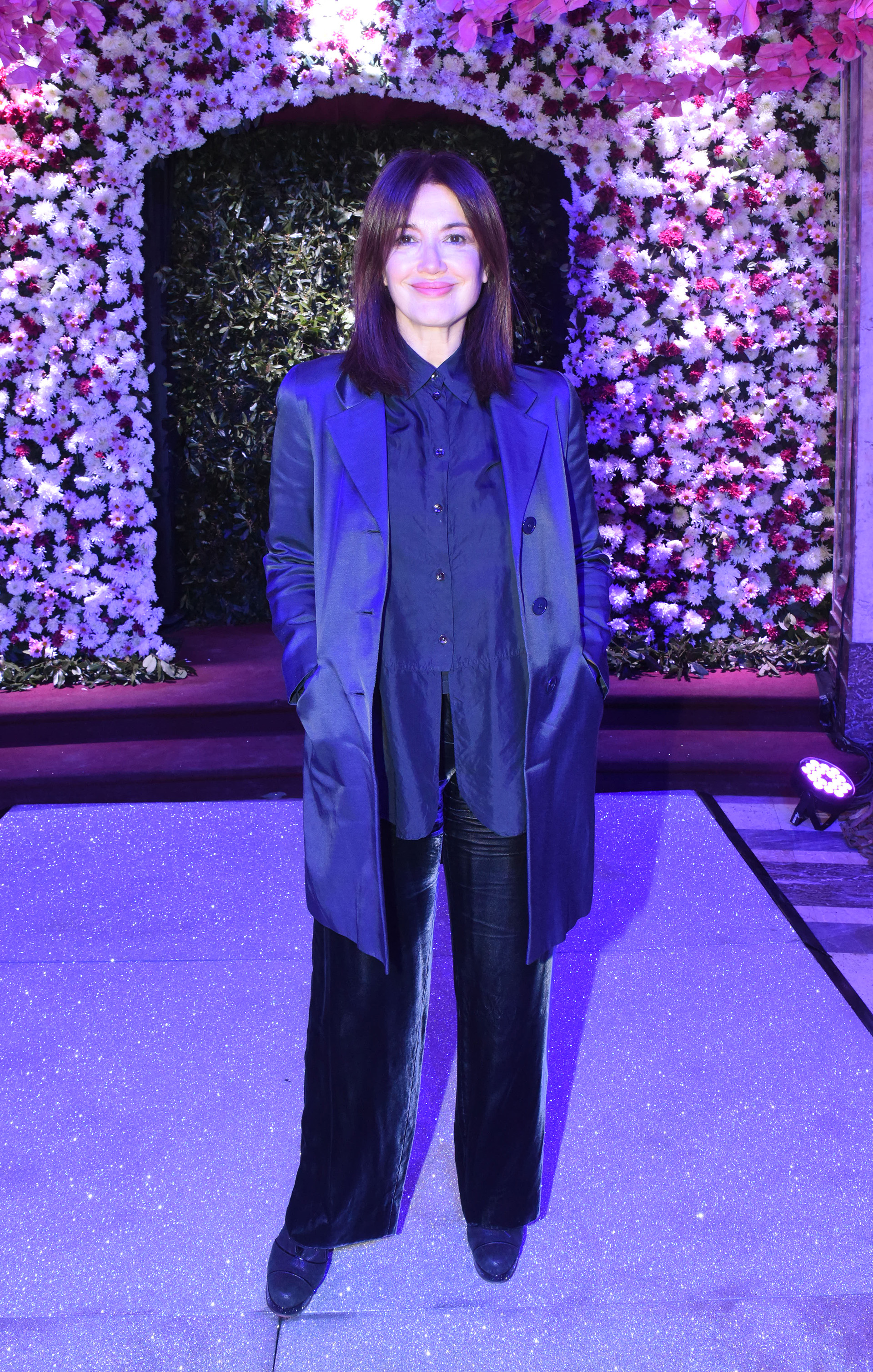 La actriz Andrea Bonelli con un look total black de pantalón, camisa y trench