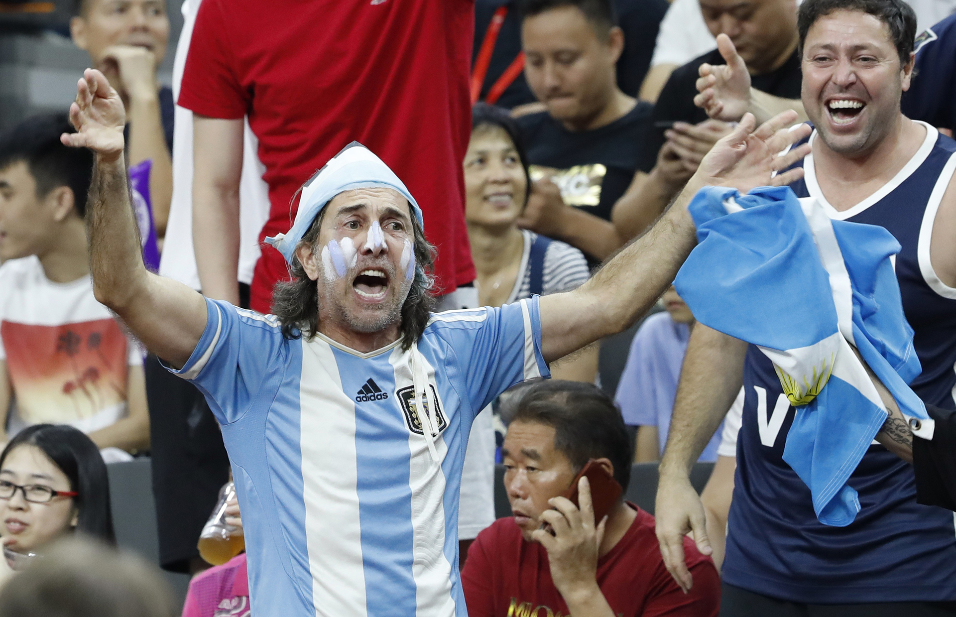 La hinchada Argentina, siempre presente en los mundiales, con simpatizantes chinos que disfrutan del encuentro hablando por teléfono.