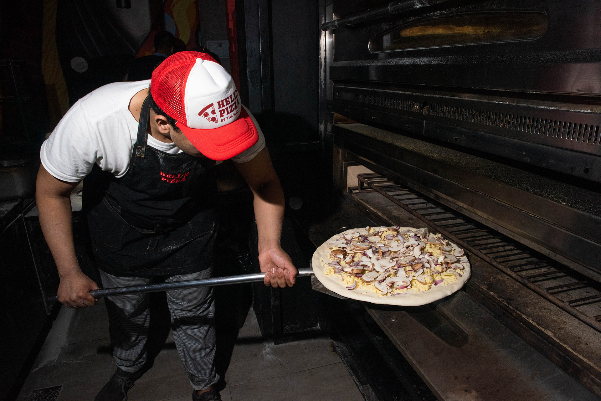 En plena acción. Los maestros pizzeros de Hell’s Pizza ponen sus creaciones en el horno