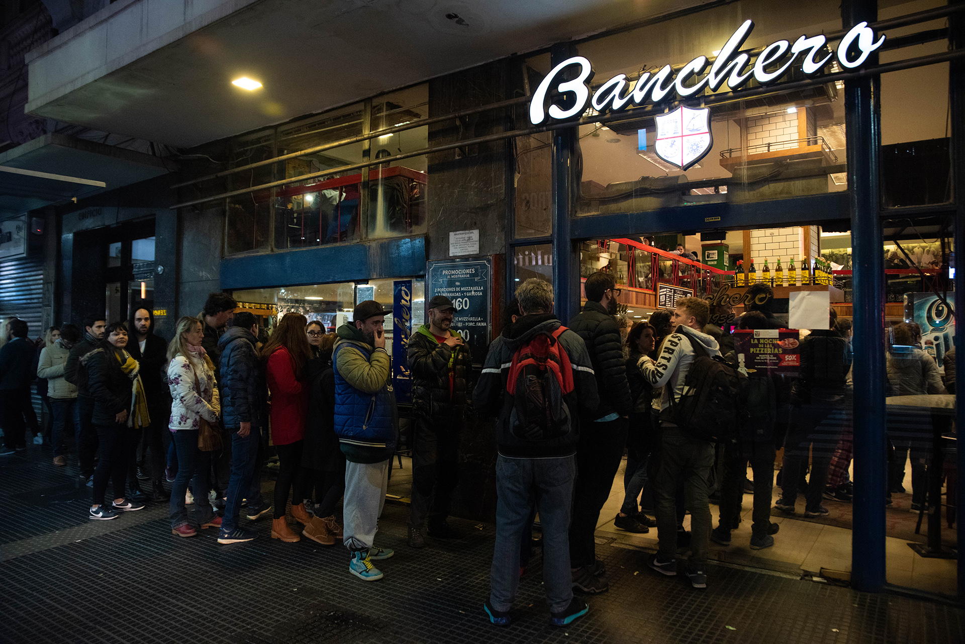 Comensales ansiosos haciendo fila en la puerta de Banchero esperando por una mesa en el salón de doble piso en la esquina de Avenida Corrientes y Talcahuano