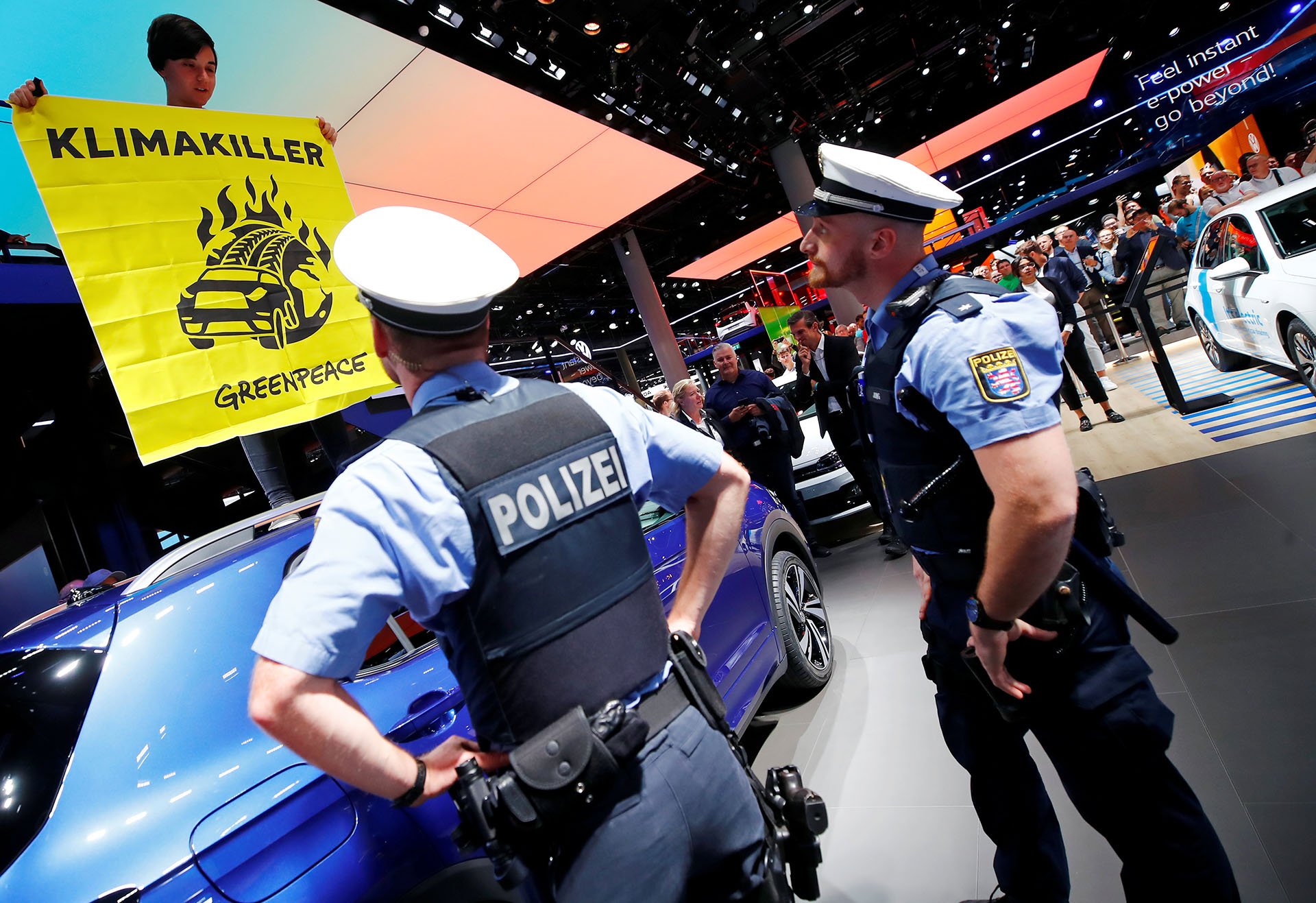Oficiales de policía observan cómo un activista de Greenpeace se subió a un coche expuesto como señal de protesta contra el calentamiento global