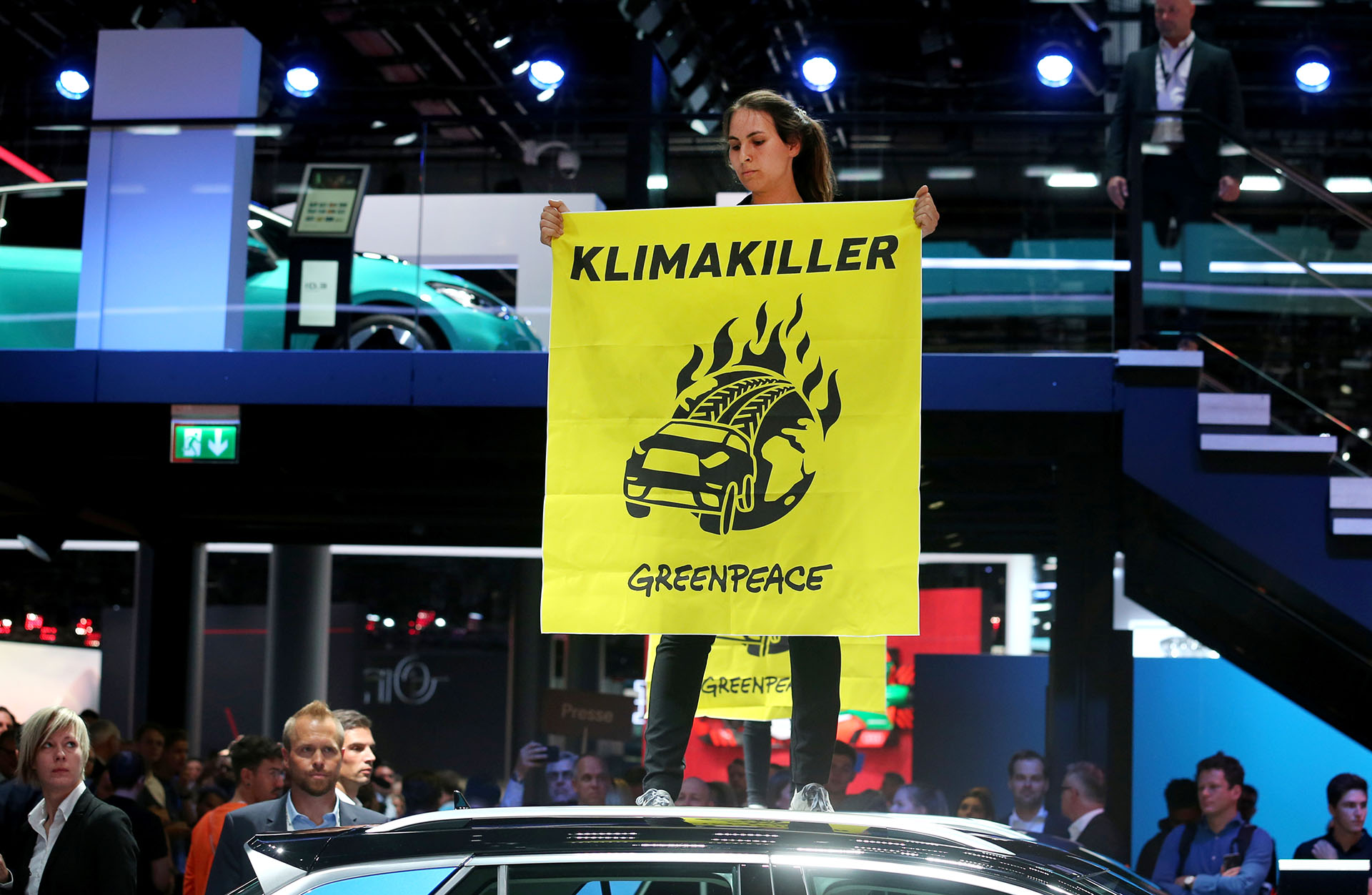 Una activista de Greenpeace se sube a un coche exhibido mientras protesta contra el calentamiento global durante la visita de la canciller alemana Angela Merkel al Salón Internacional del Automóvil de Frankfurt