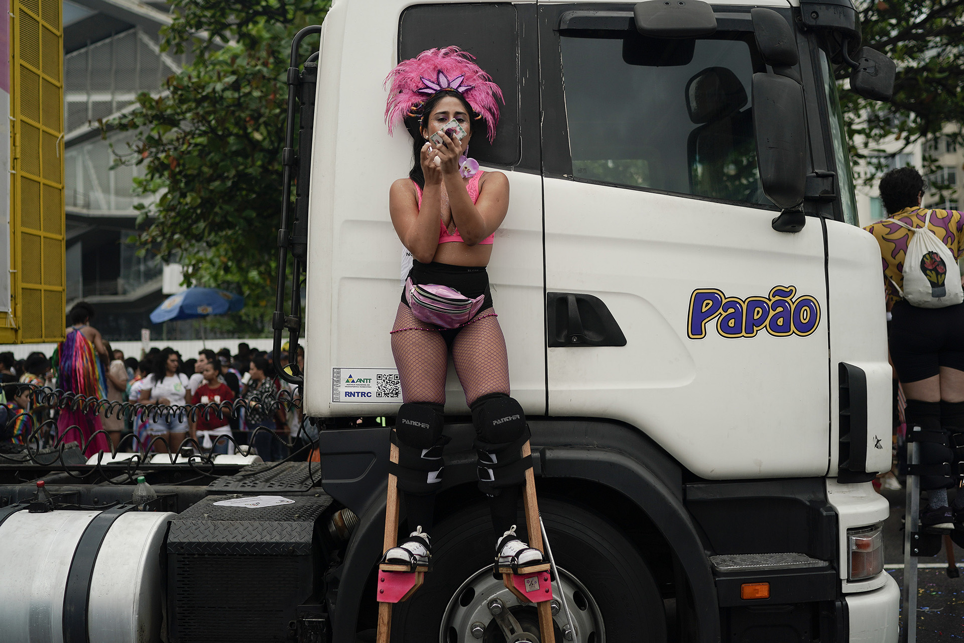 Una mujer en zancos retoca su maquillaje durante el desfile. (Foto AP / Leo Correa)