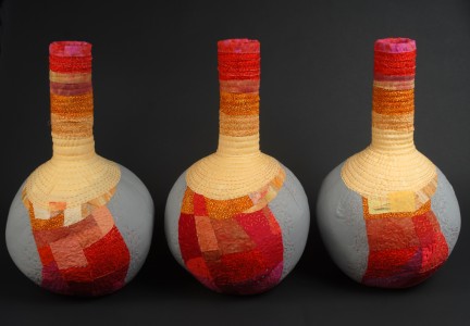 Three beaker shaped fiber vessels in reds and oranges
