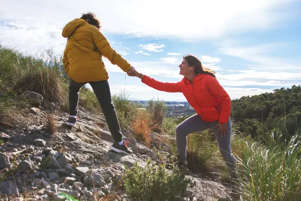 Woman helping another up a hill