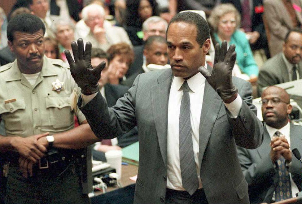 O.J. Simpson shows the jury a new pair of Aris extra-large gloves, similar to the gloves found at the Bundy and Rockingham crime scene 21 June during his double murder trial in Los Angeles. Depety Sheriff Roland Jex(L) and Prosector Christopher Darden(R) look on. Photo: Getty Images POO/AFP