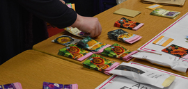 A person in a coat holding a stack of various seed packets.