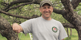 Joel Howie leans on one of his apple trees