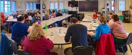 image of people sitting at round tables in a classroom