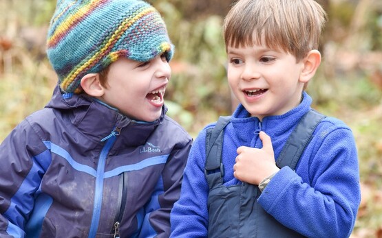 Two young boys sitting together in warm outdoor clothes.