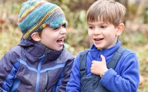 Two young boys sitting together in warm outdoor clothes.