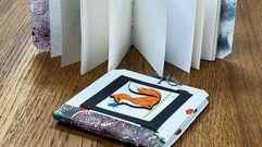 Two small hand-made books, one laying flat and the other spread out.