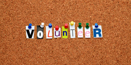 letters forming the word "volunteer" on a cork board