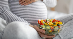 image showing a pregnant womans belly with plate of food