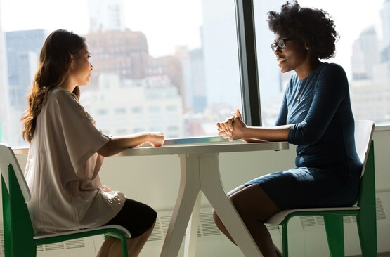 Two women sitting beside table and talking