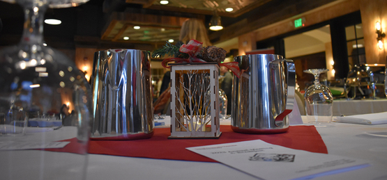 A table set with a candle holder centerpiece that resembles a winter tree, and a pitcher of water on each side.