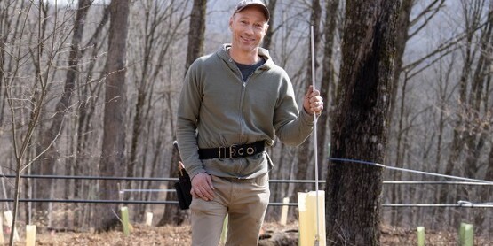 Aaron Wightman (the instructor) standing in a maple field