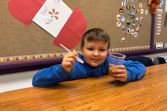 3rd grade student taste testing the applesauce made by the class