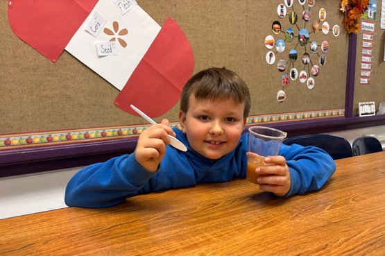 3rd grade student taste testing the applesauce made by the class