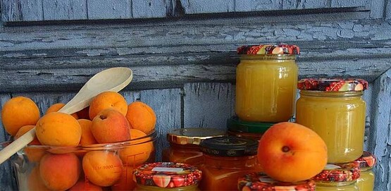 fresh apricots in a bowl, next to several jars of preserves