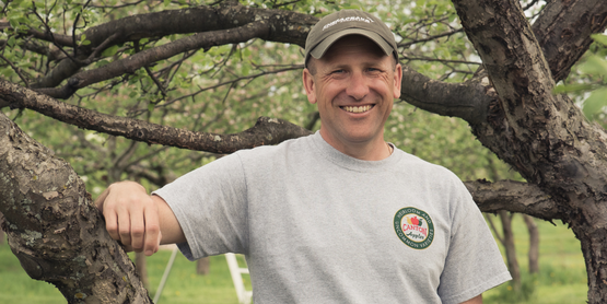 Joel Howie leans on one of his apple trees
