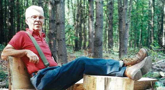 Eric Rasmussen relaxes on a chair and stool he just carved with a chainsaw.