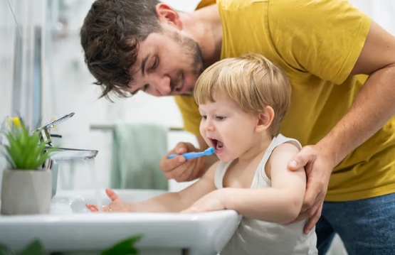 dad helping son brush teeth